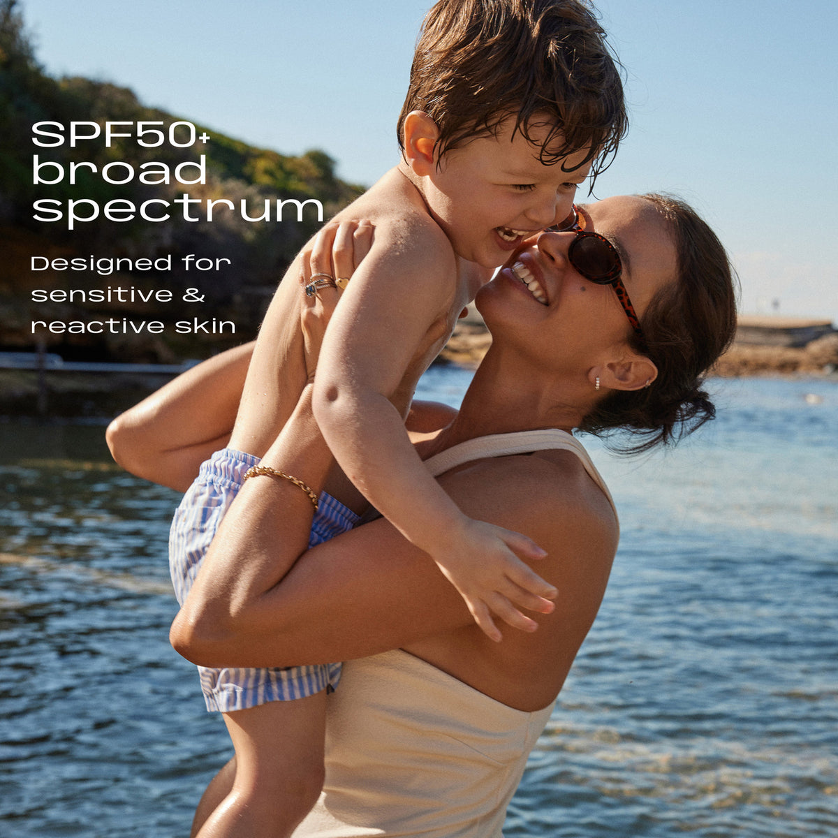 Mum lifting her laughing son at the beach. SPF50+ broad spectrum, designed for sensitive and reactive skin